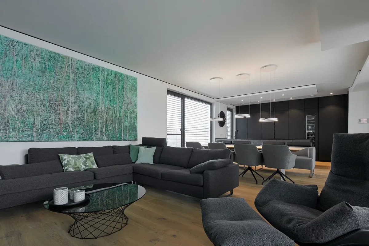 Die gedeckte Farbpalette der Sitzmöbel verbindet die drei Bereiche Wohnen, Essen und Kochen dieser Wohnküche perfekt miteinander.