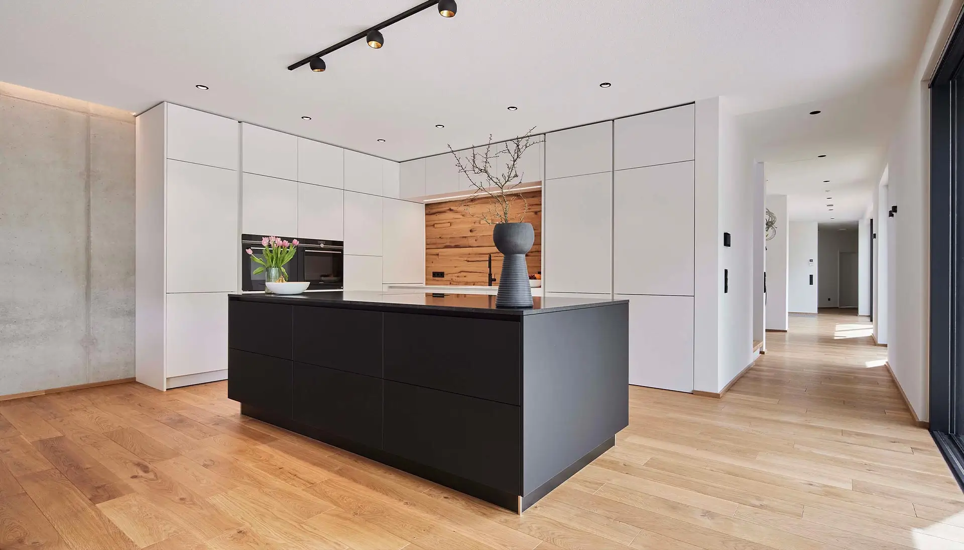 Die elegante, moderne Küche ist Teil eines offenen Wohnkonzepts. Versteckt hinter Raumhohen-Schrankfronten befindet sich der Zugang zur Speisekammer- eine wahre premium Küche.